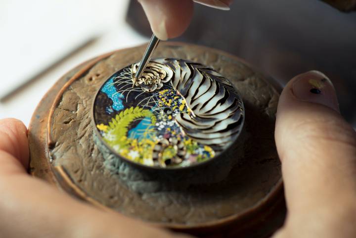 Sur ce cadran de montre Hermès, Anita Porchet exprime toute sa maîtrise de la technique d'émail cloisonné dans la réalisation d'une tête de tigre (en haut à droite). Chaque couleur est clairement délimitée par un fil d'or, délicatement appliqué à la main. Il en résulte un effet de profondeur surprenant et enchanteur.