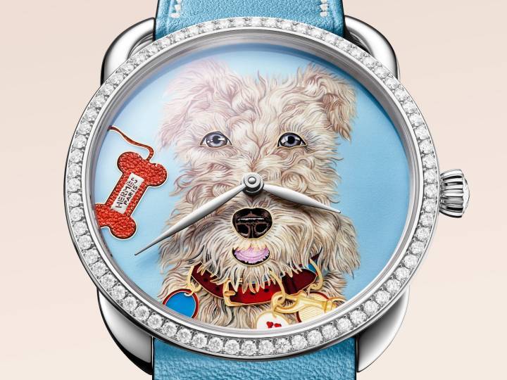 Montre Hermès Arceau Jour de Casting (2025). Techniques: peinture miniature (Debora Martinez) et émail cloisonné (équipe Miniare). L'improbable «portrait» de Taco – inspiré du carré de soie dessiné par l'artiste Liz Stirling – étonne et amuse. Comme coiffée, poudrée et maquillée, la mascotte nous regarde droit dans les yeux et semble prête à monter sur les planches d'un théâtre ou à défiler dans un concours d'élégance. Le temps d'une image, Hermès nous invite à faire un pas de côté et à oublier les thèmes anxiogènes qui peuvent bien attendre un peu.