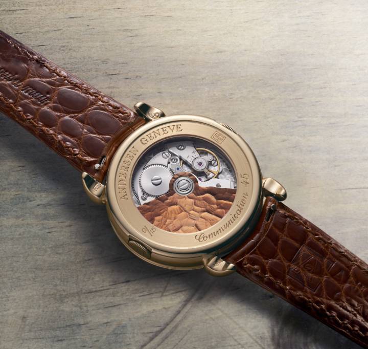Pour marquer son 45ème anniversaire, Andersen Genève a créé la Communication 45, une montre à heure universelle en édition limitée qui célèbre le statut emblématique de cette complication dans l'histoire de la marque (image du haut, à côté de la montre Communication de 1990). La fonction heure universelle est assurée par un module d'une épaisseur de seulement 0,9 mm, constamment perfectionné depuis sa création en 1990. Comme du côté cadran, la masse oscillante est en or bleu 21ct couleur cognac. Les ponts et le coq ont une finition «frosted» qui fait ressortir le délicat anglage du mouvement. 