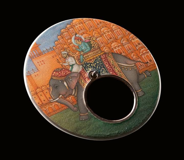 Miniature peinte à la main par Shakir Ali, lauréat du Padma Shri et l'un des peintres miniaturistes les plus respectés d'Inde. Utilisant un pinceau aussi fin qu'un cheveu et des pigments naturels issus de pierres précieuses selon des recettes secrètes et ancestrales, l'artiste a représenté une procession royale devant le célèbre Hawa Mahal de Jaipur – le Palais des Vents – qui célébrait en 2025 son 225ème anniversaire.