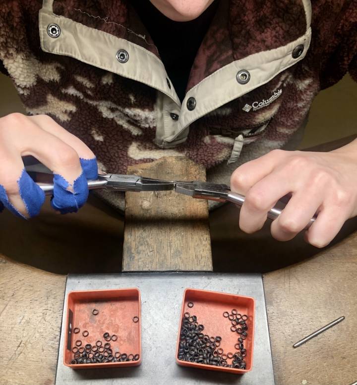 Mise à la taille de maillons. Le geste répété inlassablement provoque de nombreuses cloques et ampoules, comme en témoignent les rubans de protection bleus de la jeune chaîniste évoluant dans l'atelier de Laurent Jolliet.