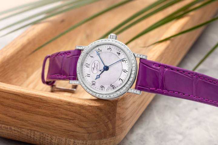 La nouvelle Classique Dame 8068 arbore un cadran en nacre très finement guilloché à la main, dont le tour d'heure est composé de chiffres arabes Breguet qui lui confèrent une légèreté visuelle, à la fois classique, moderne et raffinée. La lunette de son boîtier de 30 mm en or blanc ou or rose et ses attaches sont serties de 64 diamants taille brillant, et sa couronne d'un diamant cabochon.