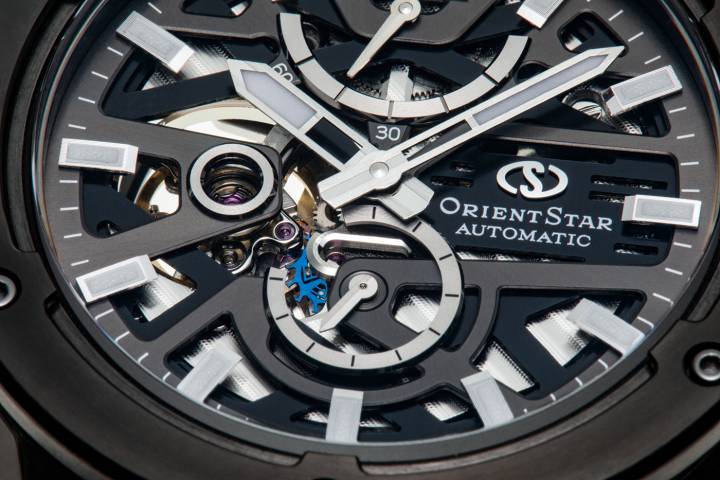 Le Calibre F8F64 avec roue d'échappement silicium et 60 heures de réserve de marche, une première pour un mouvement automatique Orient Star. La roue d'échappement, teintée bleu, est visible à 6h sous la platine partiellement évidée de la nouvelle Avant-Garde Skeleton. La disposition du cadran en deux couches a été précisément calculée pour que toute frontière entre couches s'annule. Les aiguilles des secondes sont disposées de manière à se détacher de la platine supérieure, ce qui donne une impression de profondeur et de dimension à la structure distincte du squelette. Le verre saphir à revêtement SAR réduit la réflexion de la lumière de 99% et permet de voir clairement toutes les facettes du design. Boîtier et lunette en acier inoxydable (SUS316L), finition brossée et finition miroir obtenue grâce au polissage Sallaz.