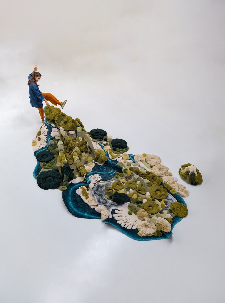 Vanessa Barragão, Dunedin, 2024. Tapis en laine touffeté à la main, 4,5 × 3,7 m. Inspirée d'un séjour à Ōtepoti Dunedin, sur l'île du Sud de la Nouvelle-Zélande, l'œuvre transpose en reliefs de laine les eaux, les plages et les collines herbeuses de la région; les «collines» sont amovibles et servent d'assises ou de dossiers.